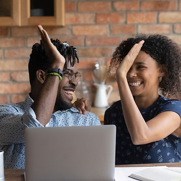 Happy excited Black mixed race couple celebrating financial success at laptop, getting inc