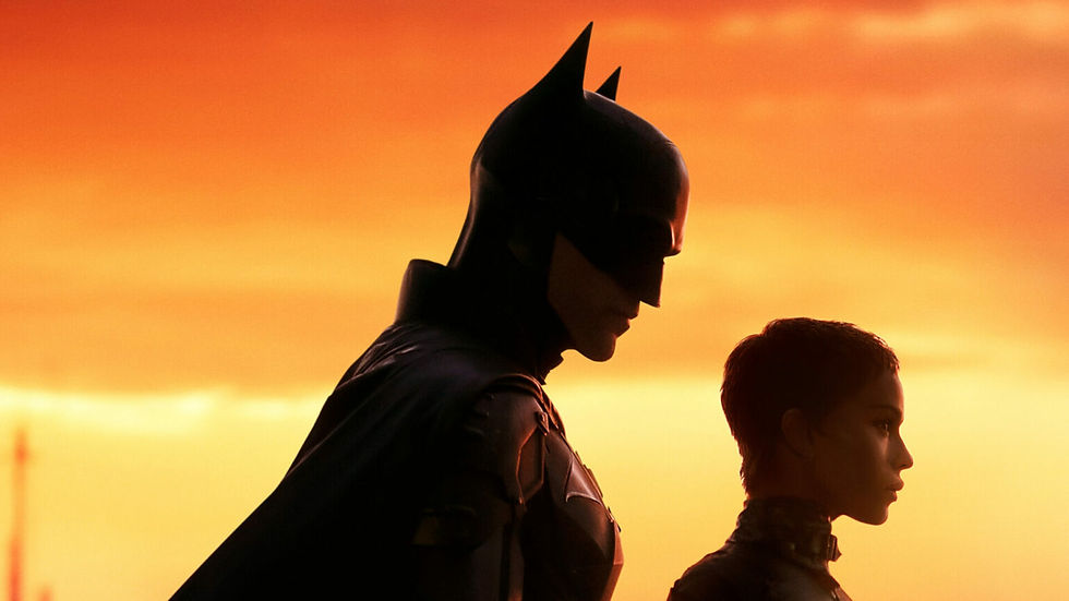 This image showcases a striking silhouette of Batman (Robert Pattinson) and Catwoman (Zoë Kravitz) against a stunning orange sunset. The dramatic lighting emphasizes their contrasting profiles, capturing the complexity of their relationship and the duality of their roles in Gotham City.