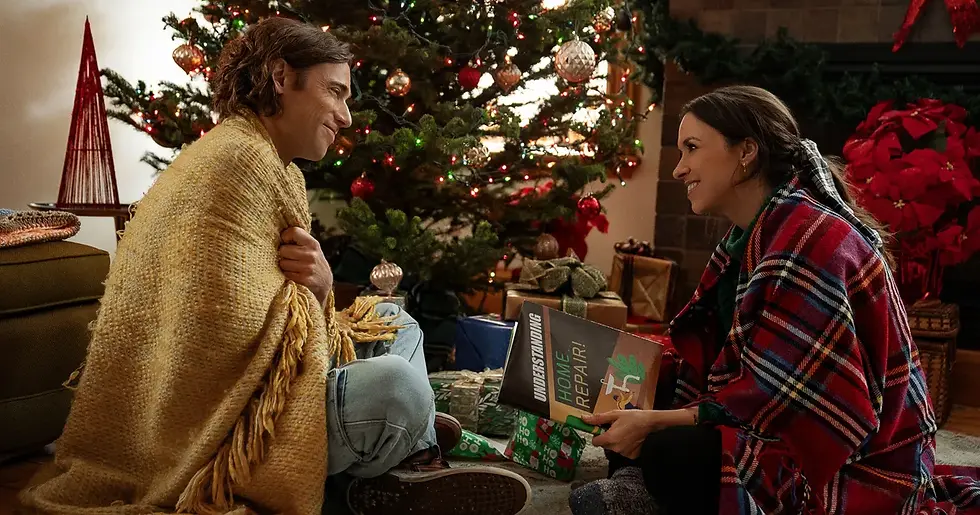 christmastree, presents, red blanket, yellow blanket, jeans, brown shoes, unwrapped presents, couple, smile, red flowers, book, brown hair, pearl earring
