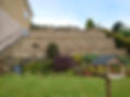 Large stepped, retaining walls, trees in background, large hedge