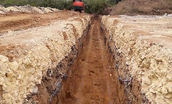 Deep trench with excavator in rural site