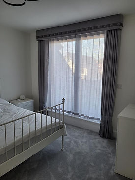 A minimalist bedroom with light gray curtains covering a large window