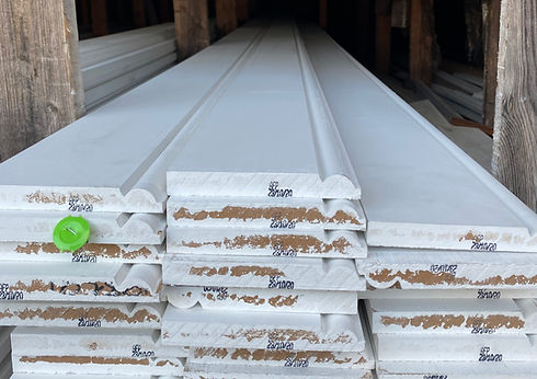 Stacked white primed wood molding boards with Prime visible.