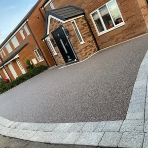 A close-up of a grey aggregate driveway showing the texture and the light block paving border
