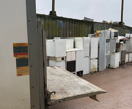 Dozens of white fridges and freezers stacked at a waste facility next
