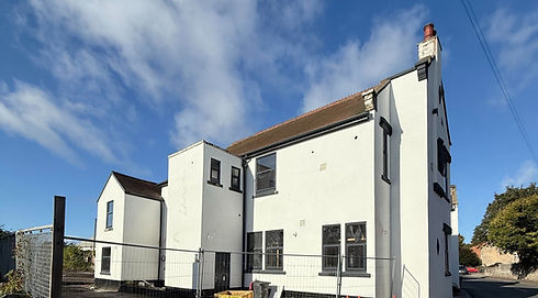 Large white house with black-framed windows, wire fence and building materials