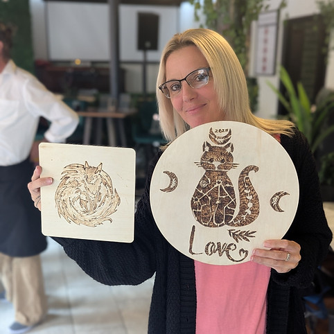 A woman with glasses holds two engraved wooden plaques