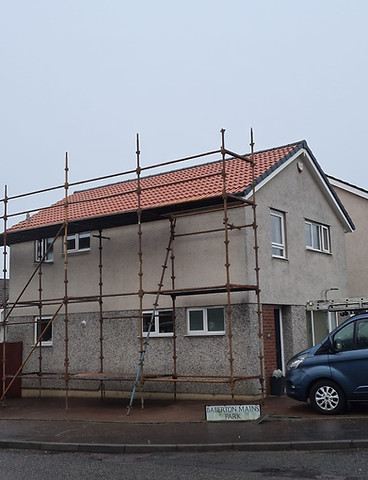 House with scaffolding and red tiled roof under construction with blue van nearby