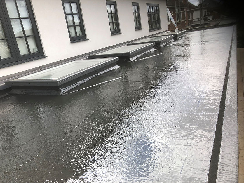 A flat roof with new skylights and a glossy, dark grey finish