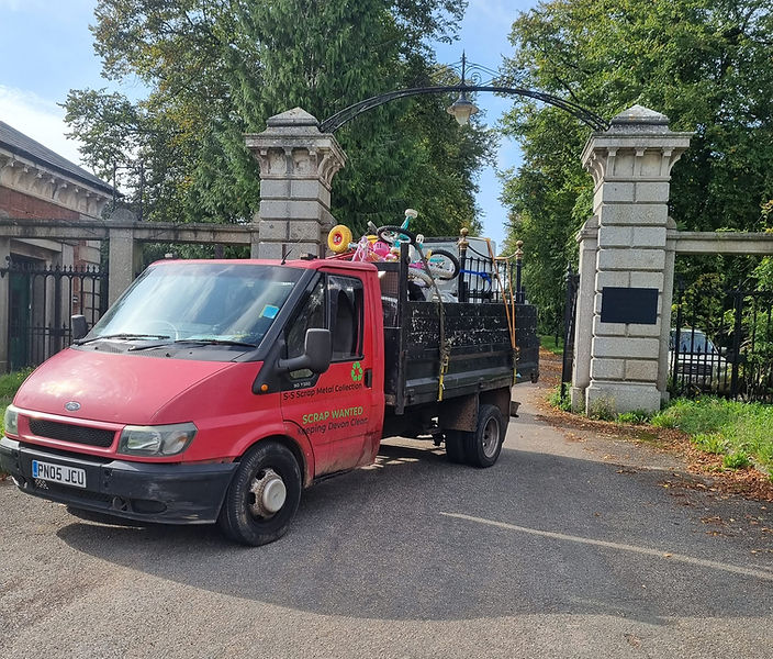 Red scrap metal collection truck filled with bicycles, furniture, and various items