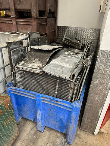 A blue plastic bin filled with stacked, dusty metal sheets and pipes