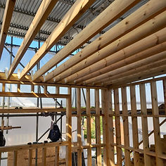 The interior of a room under construction with new timber framing for walls and a roof