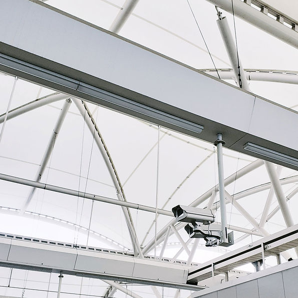 Wide-angle view of a modern ceiling with geometric metal beams and a security camera