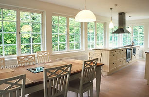 A spacious kitchen and dining area with large windows and a view of the trees