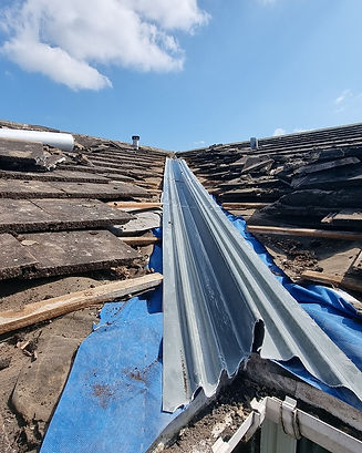 Roof repair with old tiles, blue tarp and new grey metal valley flashing