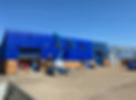 Crane parked in front of blue coloured warehouse