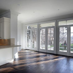 A finished room with a new kitchen counter and large white-framed French doors leading to a garden