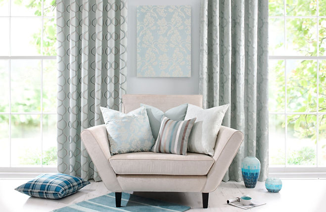 Armchair with pastel blue and white patterned cushions is set against a backdrop of elegant curtains