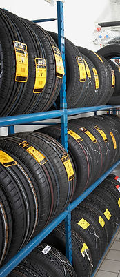 Tires neatly stacked on blue metal racks, each with yellow labels
