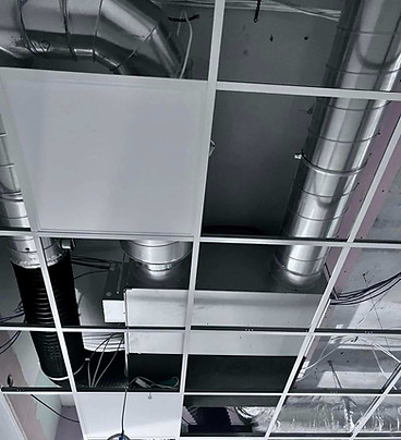Exposed ceiling showing silver HVAC ducting and a suspended grid frame during a commercial installation