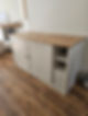 A white sideboard with a wooden top stands on a wood floor