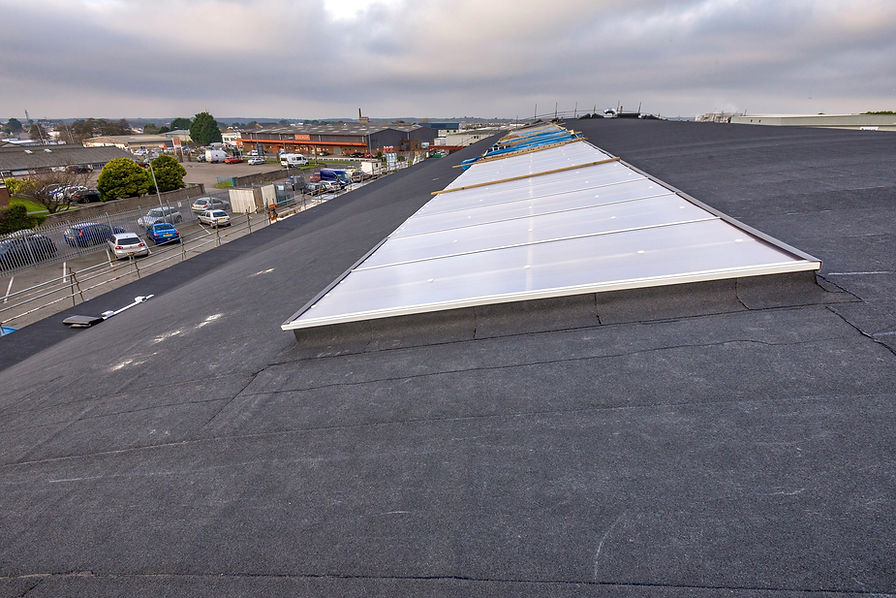A large flat roof with a new dark membrane and a long skylight