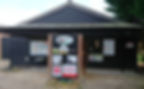 Black timber-clad building for Banks Garden Machinery with brand logos on a brick pillar