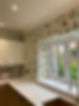 A close-up of a kitchen wall with a colourful wildflower wallpaper above a white marble-effect worktop