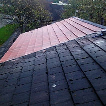 Close-up of a roof with black and pink tiles, wet from rain