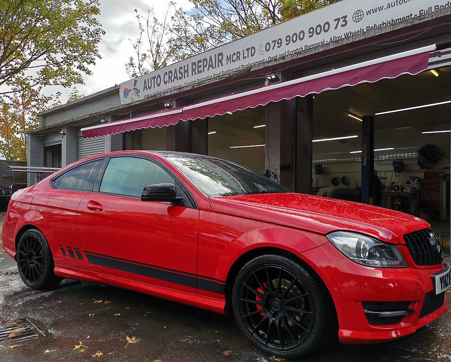 A sports car is parked outside an auto repair shop