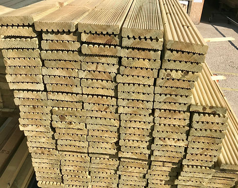 Stacked grooved timber decking boards ready for outdoor projects.