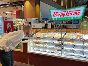 A man staring a Krispy Kreme Doughnuts at a Krispy Kreme stand.