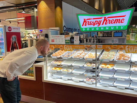 A man staring a Krispy Kreme Doughnuts at a Krispy Kreme stand.