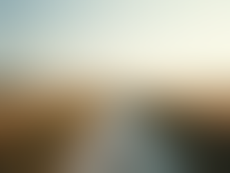 Dirt road cuts through a golden wheat field under a clear sky, with hills in the distance. Calm, serene rural landscape.