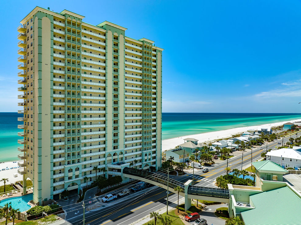 Aerial view of Celadon Beach Resort on the west end of Panama City Beach showing beachfront building, Gulf-side pool, and Gulf of Mexico shoreline
