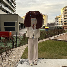 A participent holding a tufted rug that is a face with colourful dots in the hair