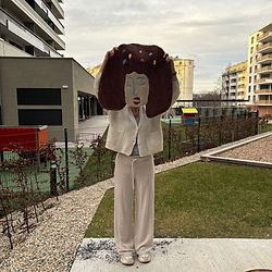 A participent holding a tufted rug that is a face with colourful dots in the hair