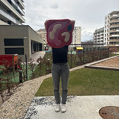 A participent holding a tufted rug that is a abstract image