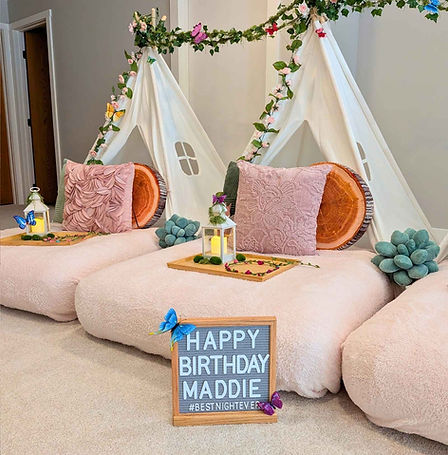 An enchated forest sleepover partyfeaturing white canvas tents decorated with ivy, flowers and sage accents and butteflies.