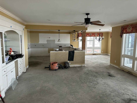 Kitchen and dining area before remodeling, no flooring, dark mustard walls. Outdated lightening.