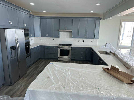 a kitchen with gray cabinets and white counter tops