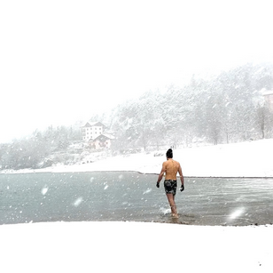 schnee, gefrorener See, mann mit mütze und Badehse bekleidet, es schneit,