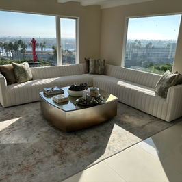 Luxurious living room with L-shaped sofa, gold table, and city view.