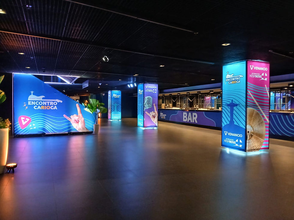 Sala de evento vazia e iluminada, com colunas azuis e rosas de Encontro Carioca, Venancio e BAR ao fundo.
