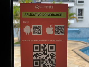 Placa vermelha do SmartStore com APLICATIVO DO MORADOR e QR codes, em frente a piscina de condomínio.