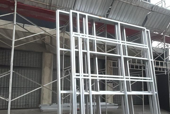 Estrutura metálica para instalação de fachada comercial em alumínio, montada em frente a um estabelecimento durante obra de comunicação visual.