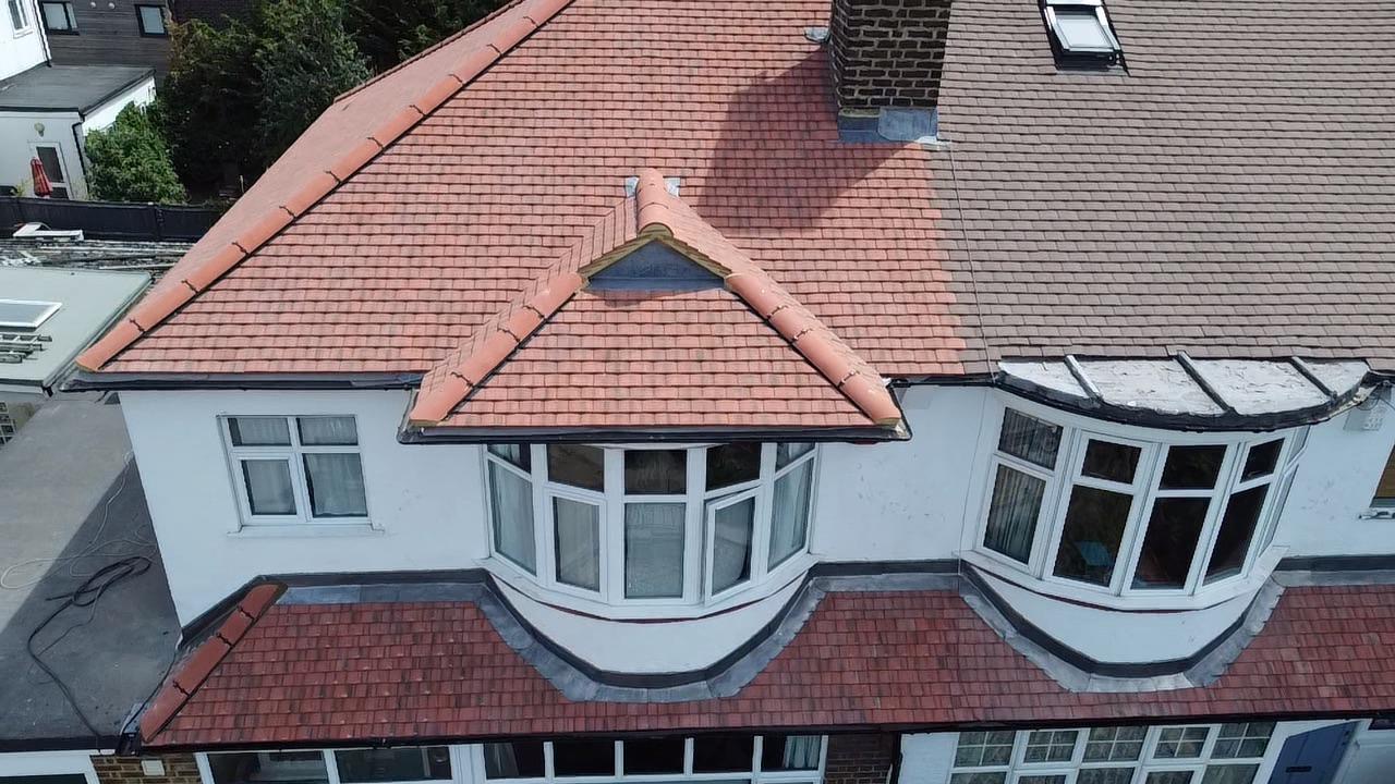 Aerial view of a completed red tiled house roof with a chimney and bay window canopy.