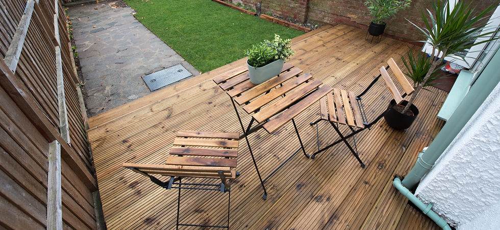 New decking installation with wooden chairs and a table, surrounded by plants