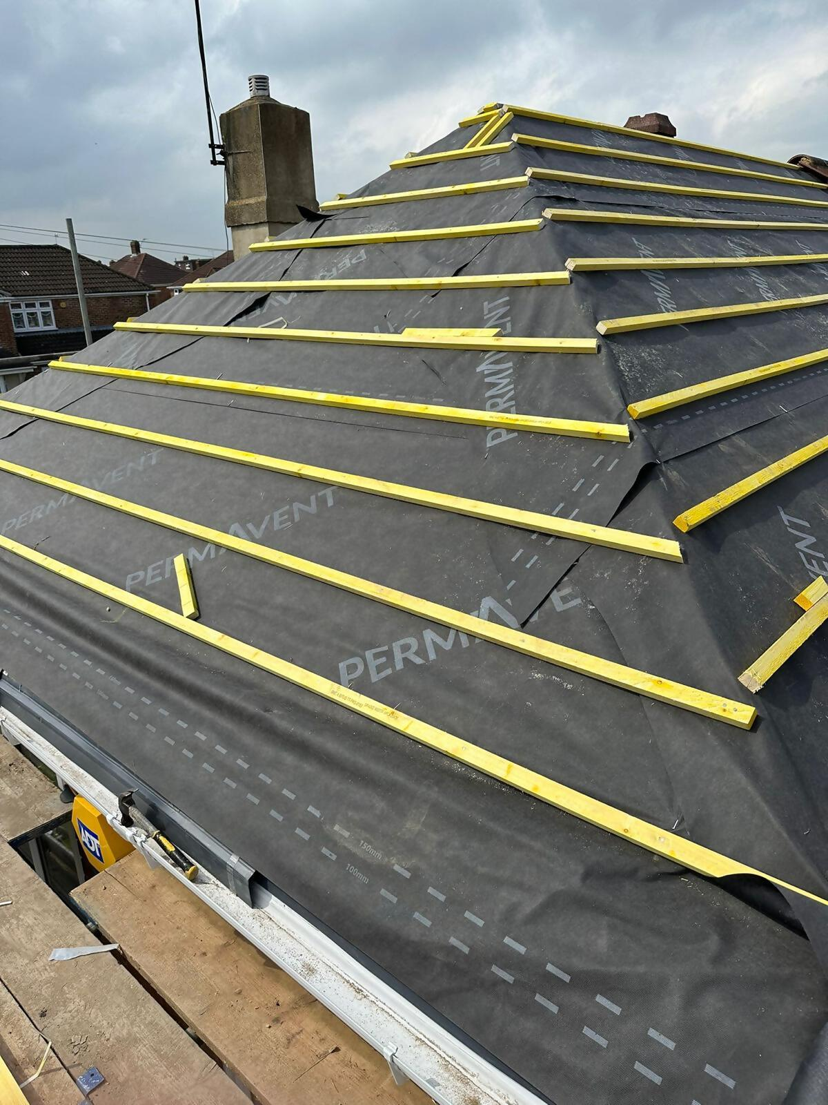 Roofer preparing hipped roof underlay and battens.