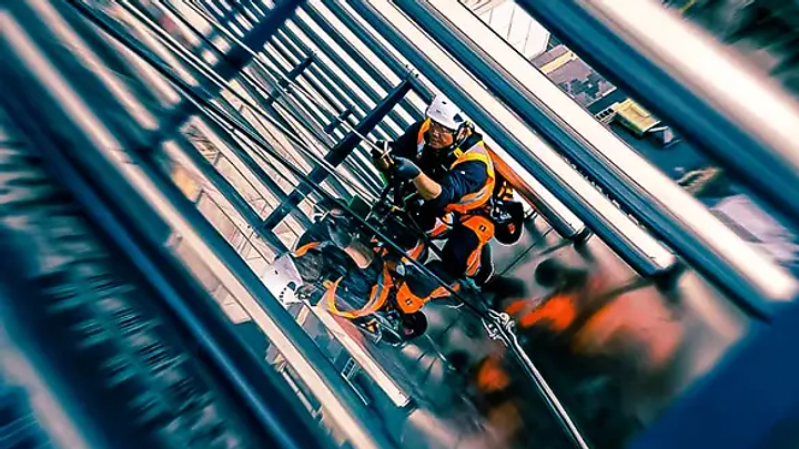 Rope access workers suspended beside a glass high-rise facade